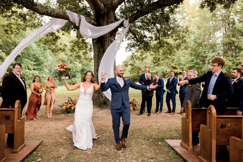 A couple cheers as they walk back down the aisle after their wedding at Avonlea Farms